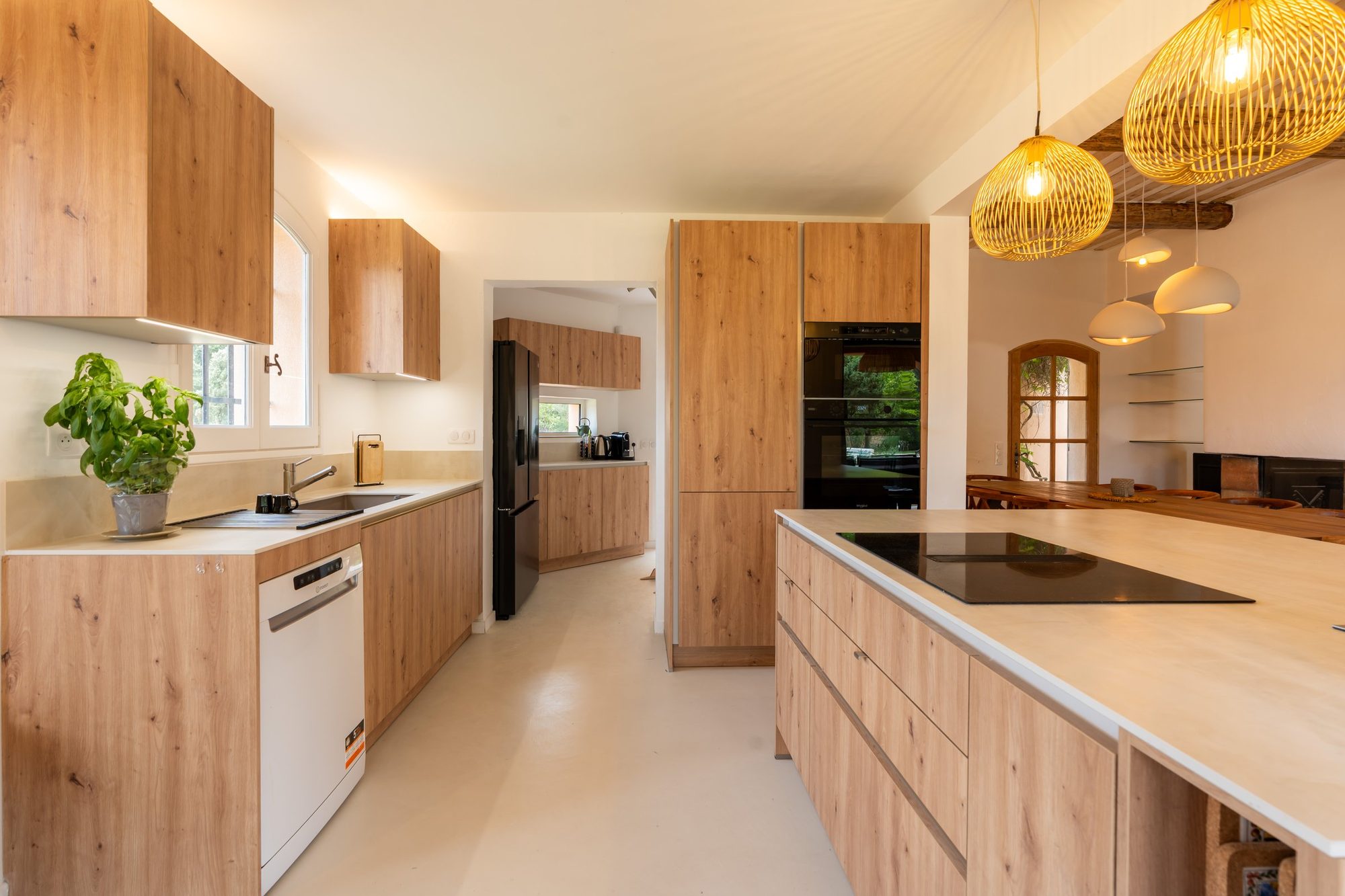 L'îlot de cuisine vu dans la longueur, plan de travail clair et façades en chêne.