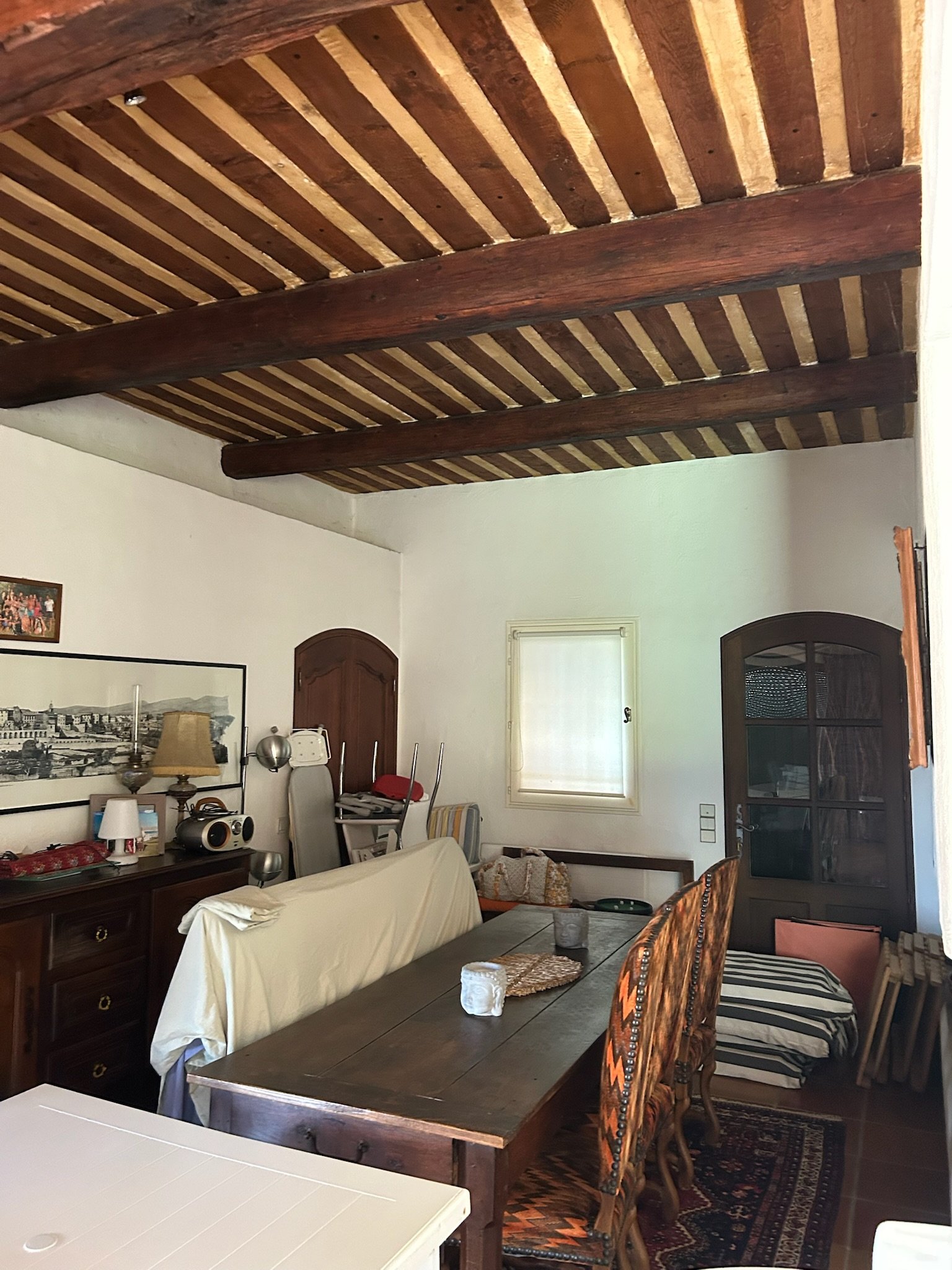 La salle à manger avant intervention : mobilier ancien dépareillé sous la charpente.