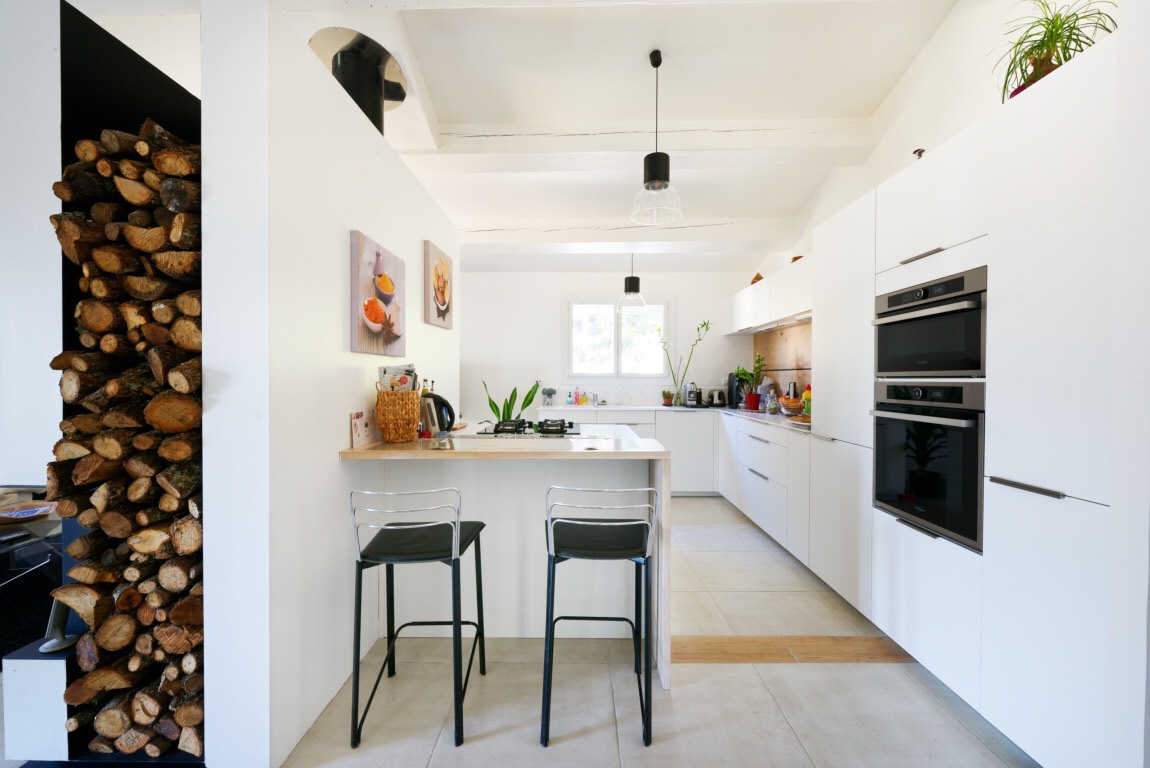 La nouvelle cuisine blanche et bois, ouverte, avec son bar et ses tabourets hauts.