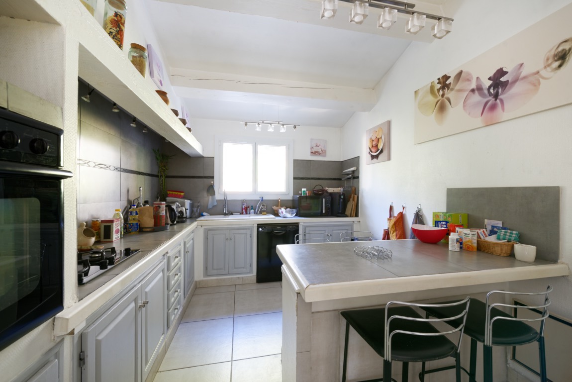 L'ancienne cuisine fermée, façades grises et plan de travail carrelé.