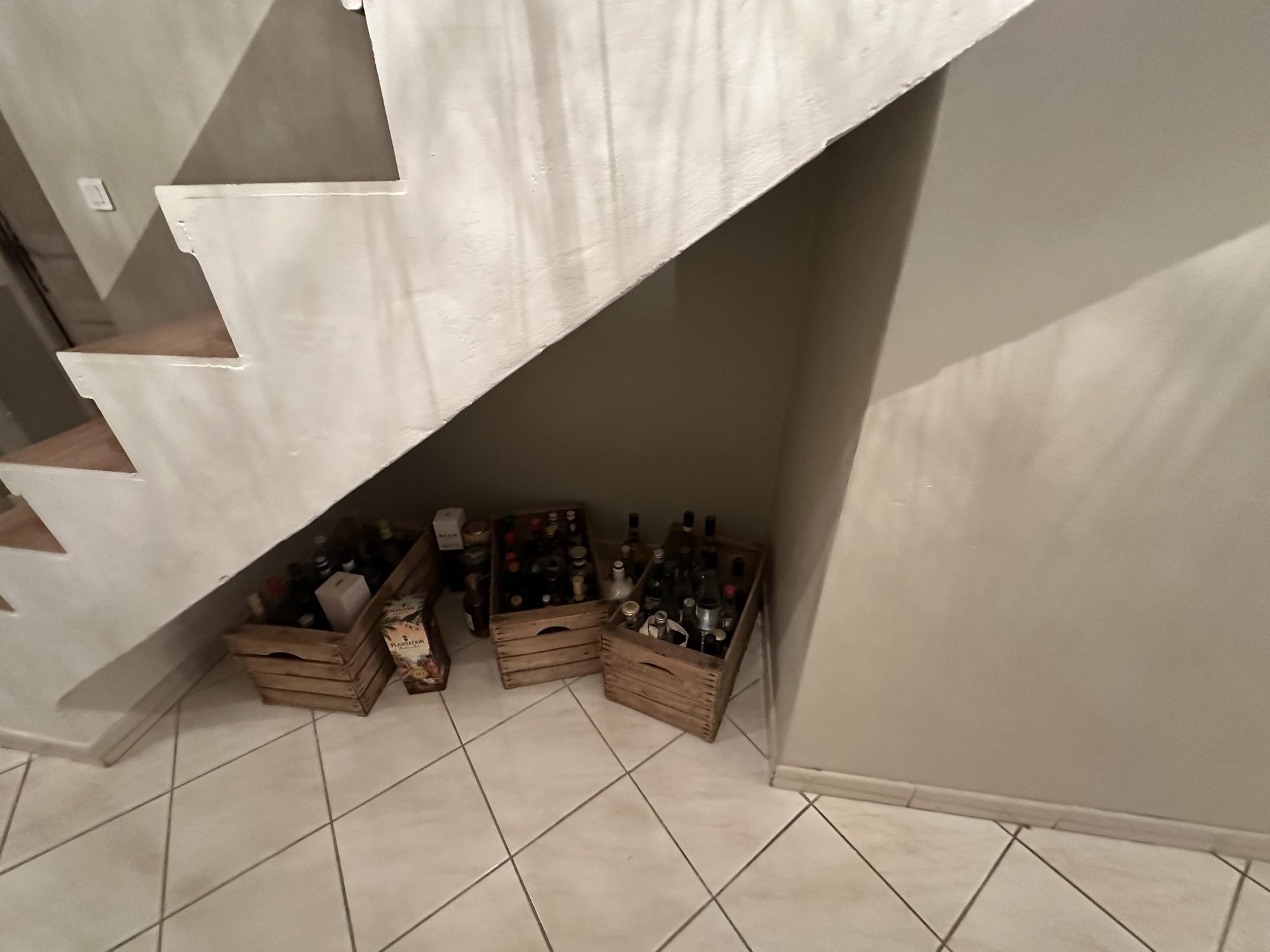 Le dessous d'escalier avant travaux, occupé par des caisses en bois.